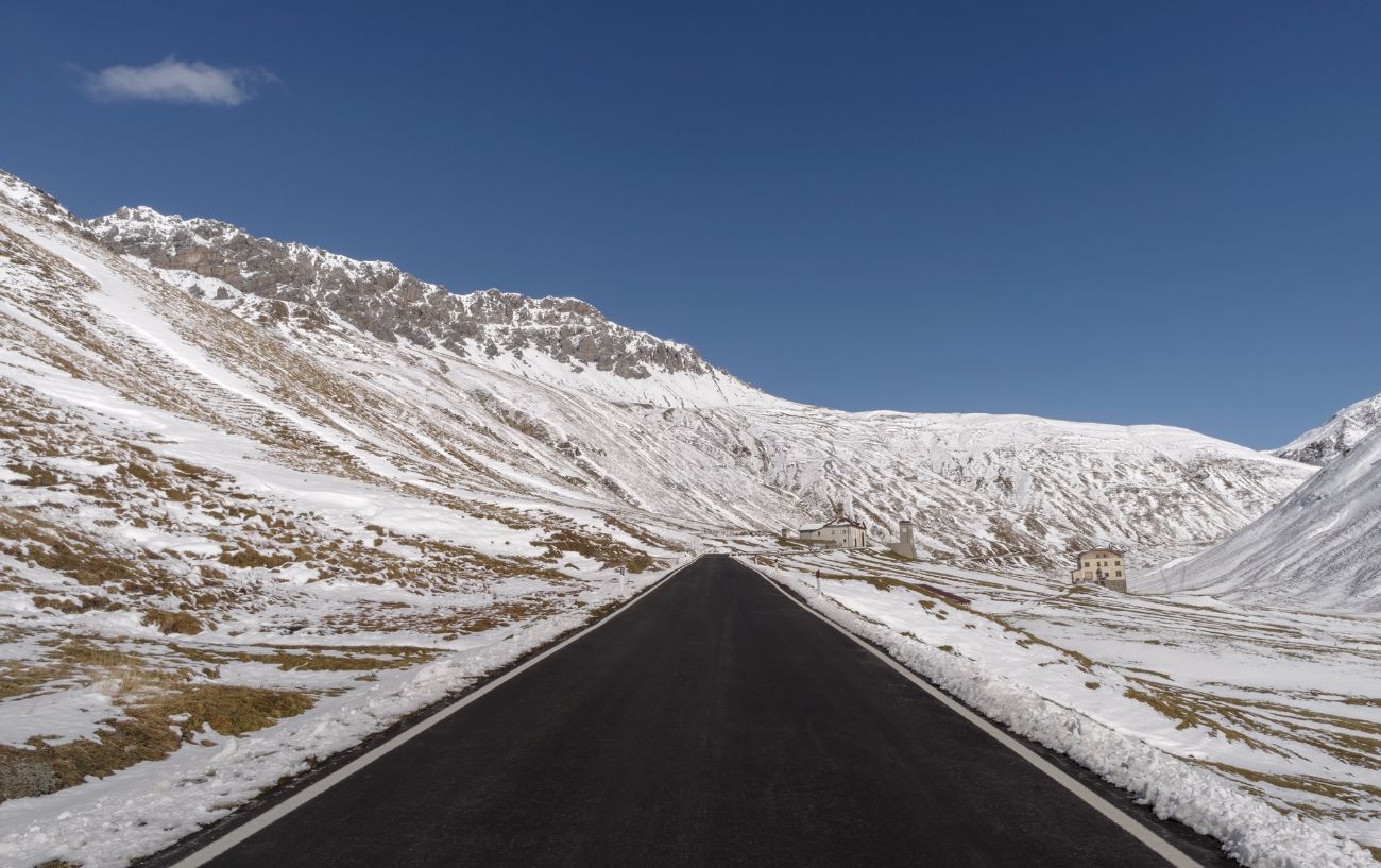A strip of black ashpalt stretches through a snow-covered landscape.