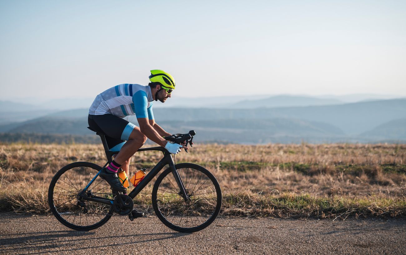 A cyclist rides past a field in the winter sun.