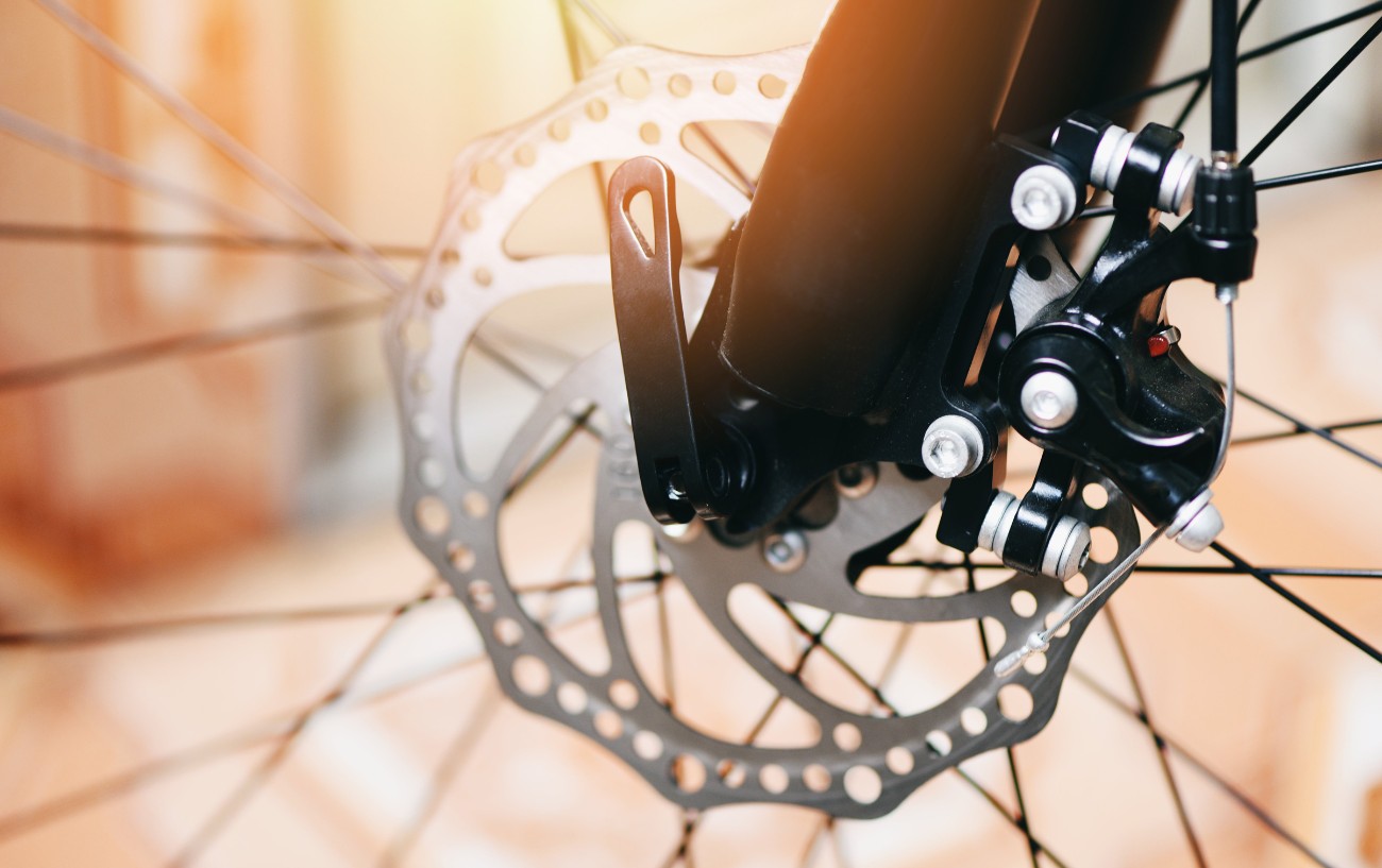 Close-up of a silver disc brake reflecting a sunset.