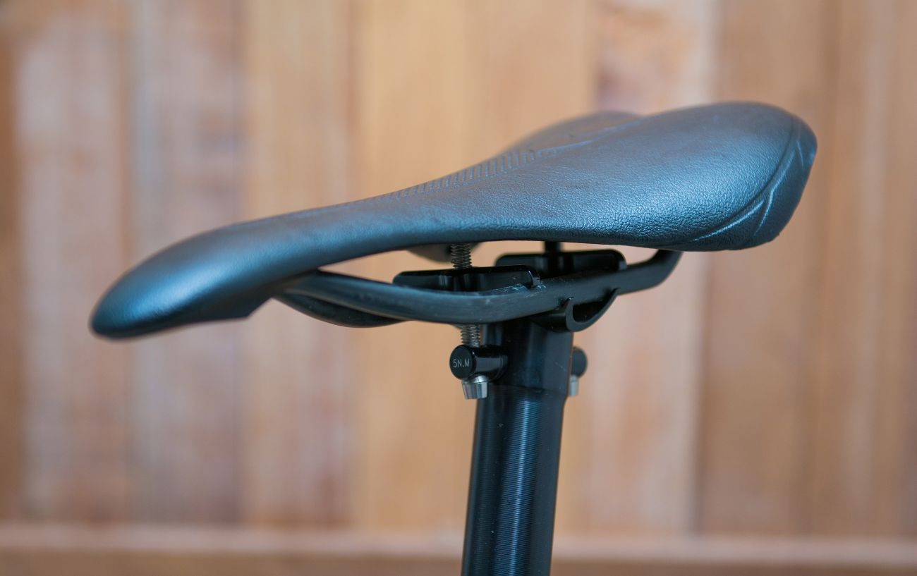 A black bicycle saddle with a wooden panel in the background.