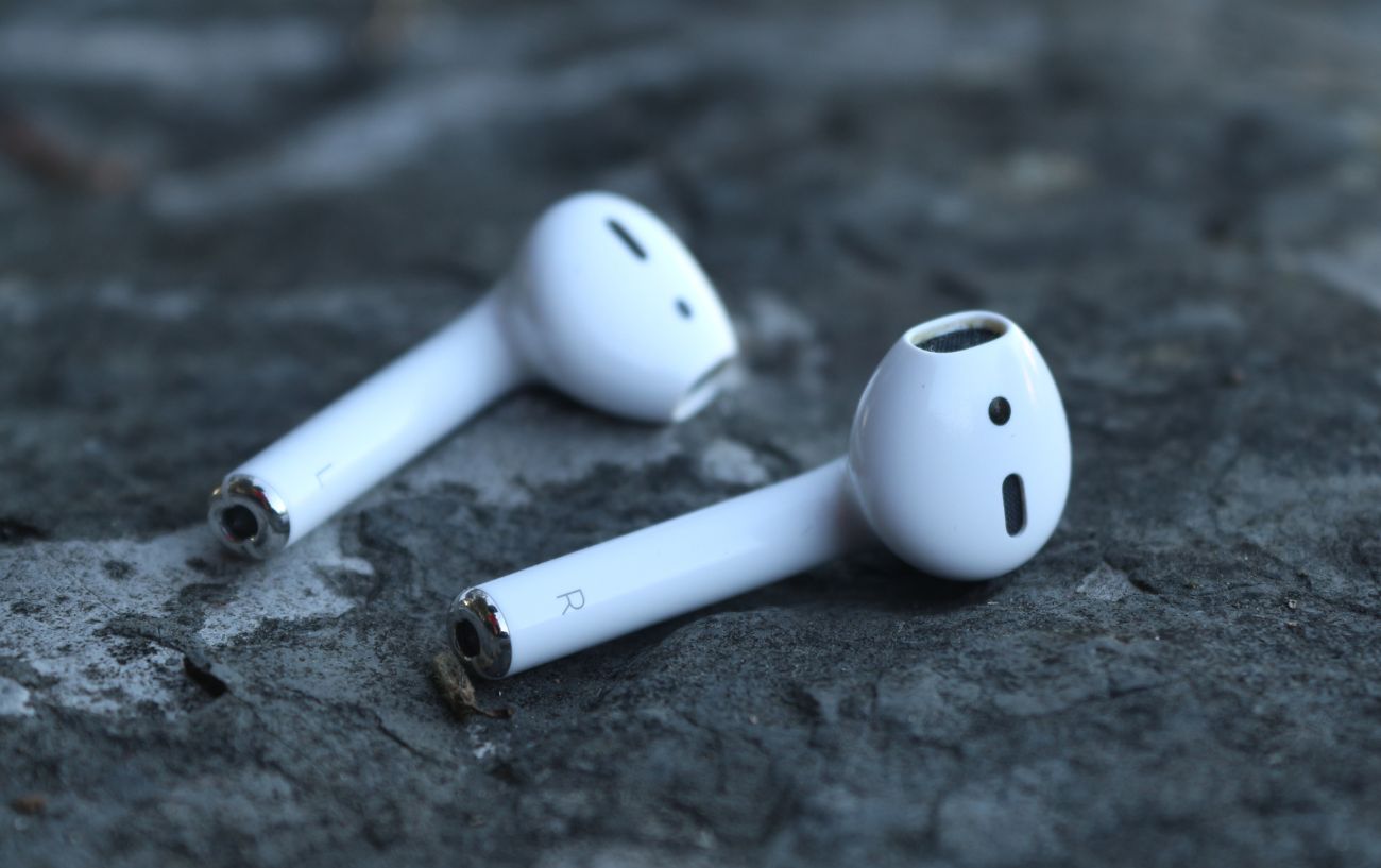A pair of white AirPods lie on a slate surface.