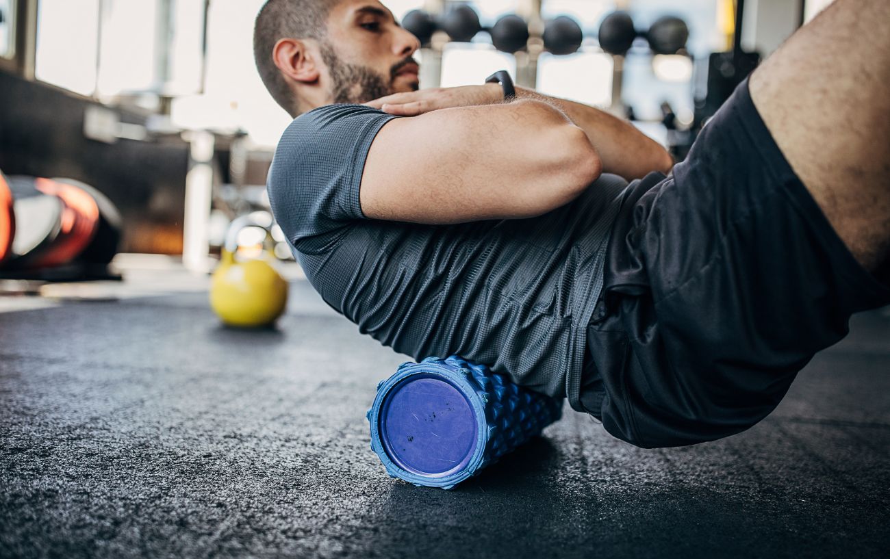 A cyclist works on his back with a foam roller.