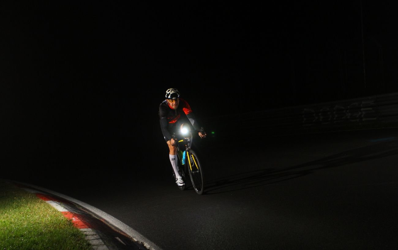 A cyclist riding at night with bike lights.