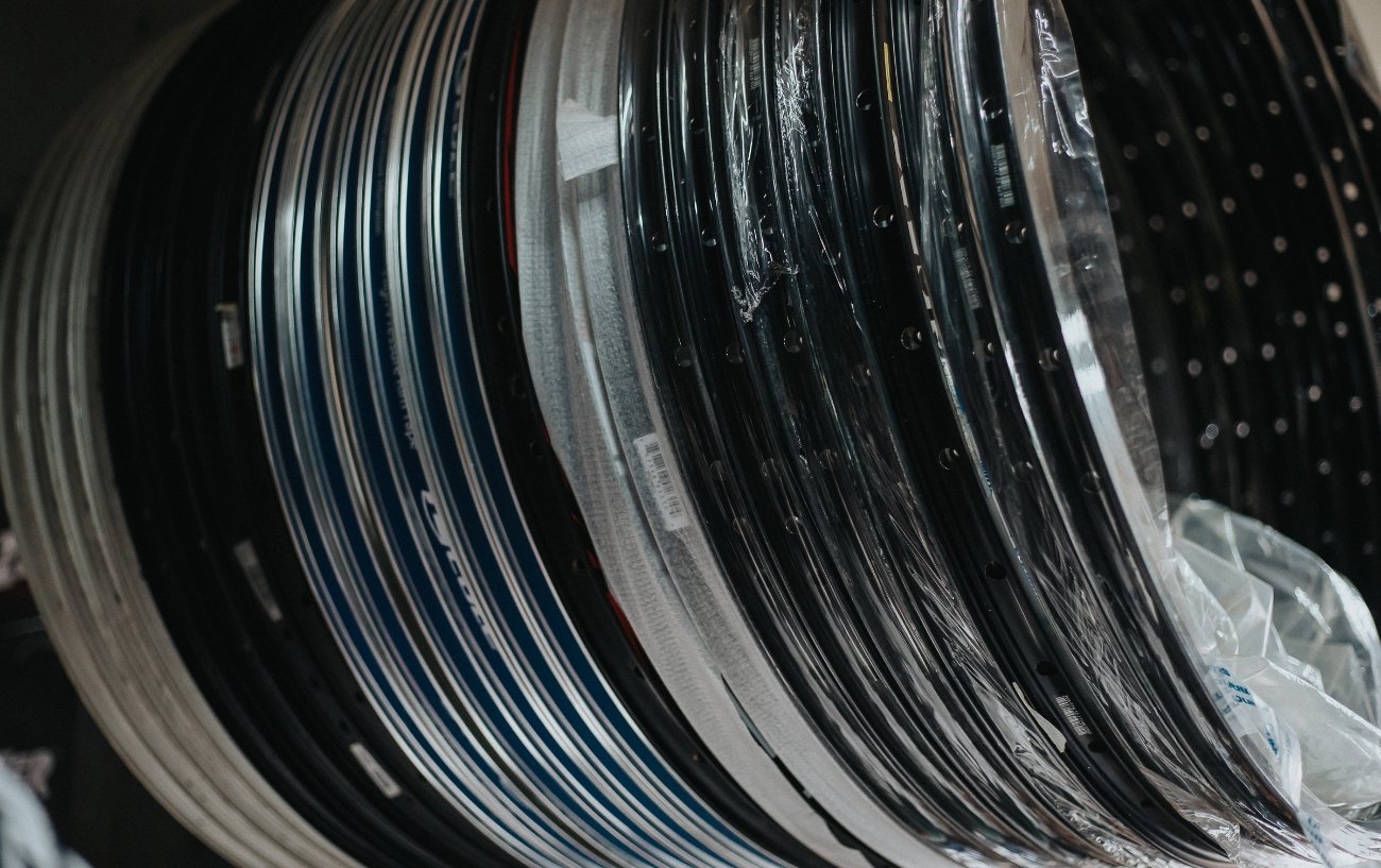 A rack of bike rims with varying widths hang from a rack in a bike shop.