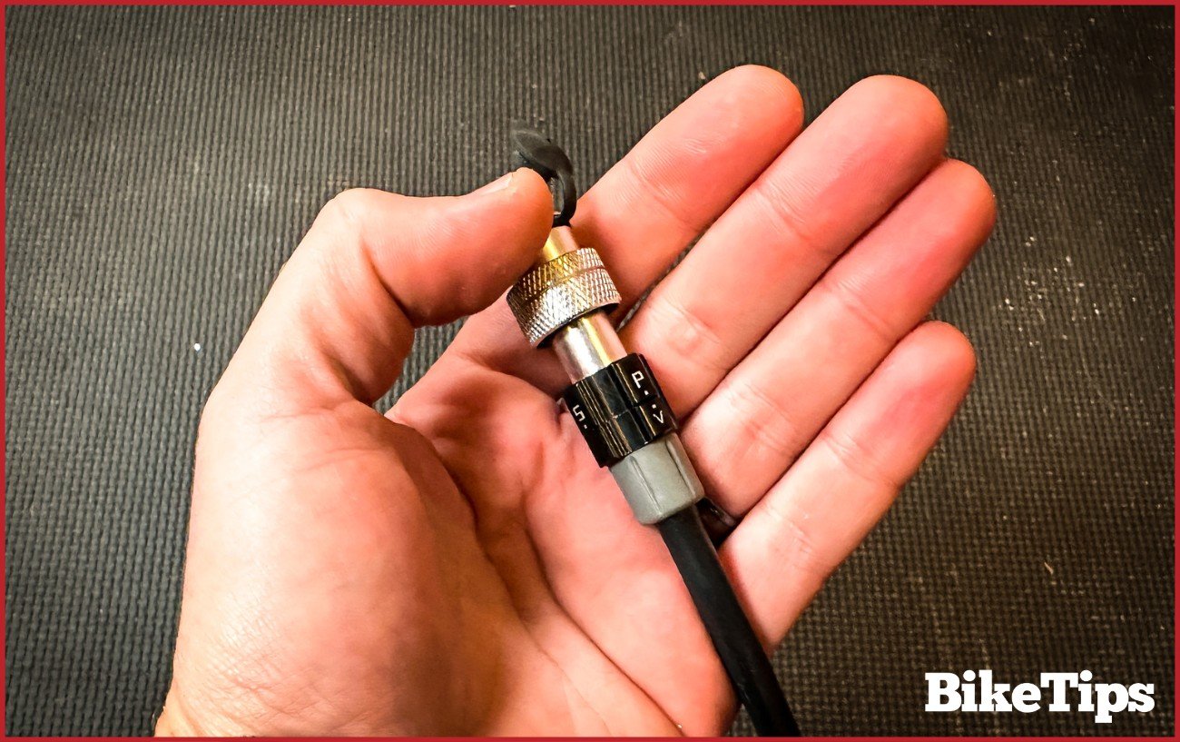 Close-up of the end hose of a hand pump in a mechanic's palm.