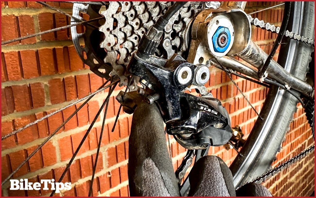 Pointing out the limit screws on the rear derailleur.