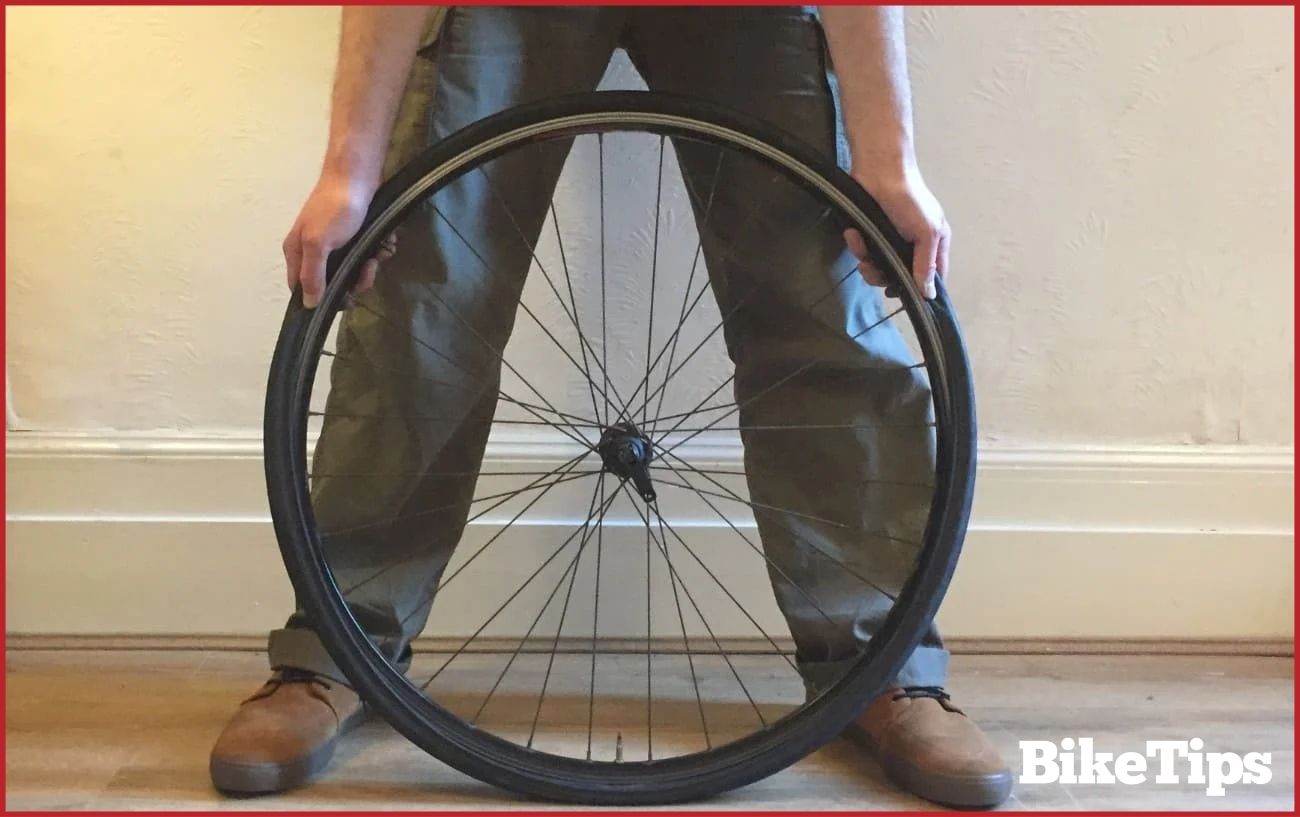 Demonstrating the technique to fit the tire back onto the rim.