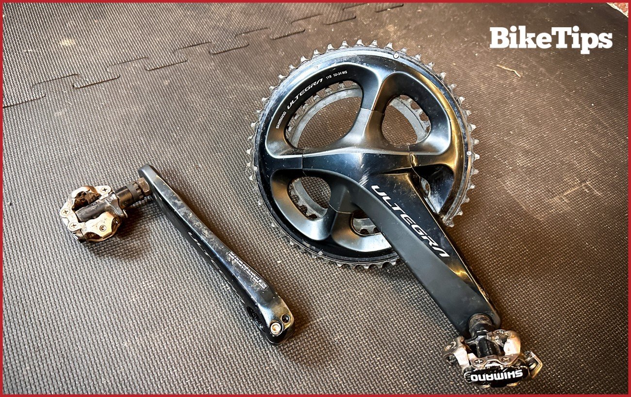 A black Ultegra crankset sits on a black floor.