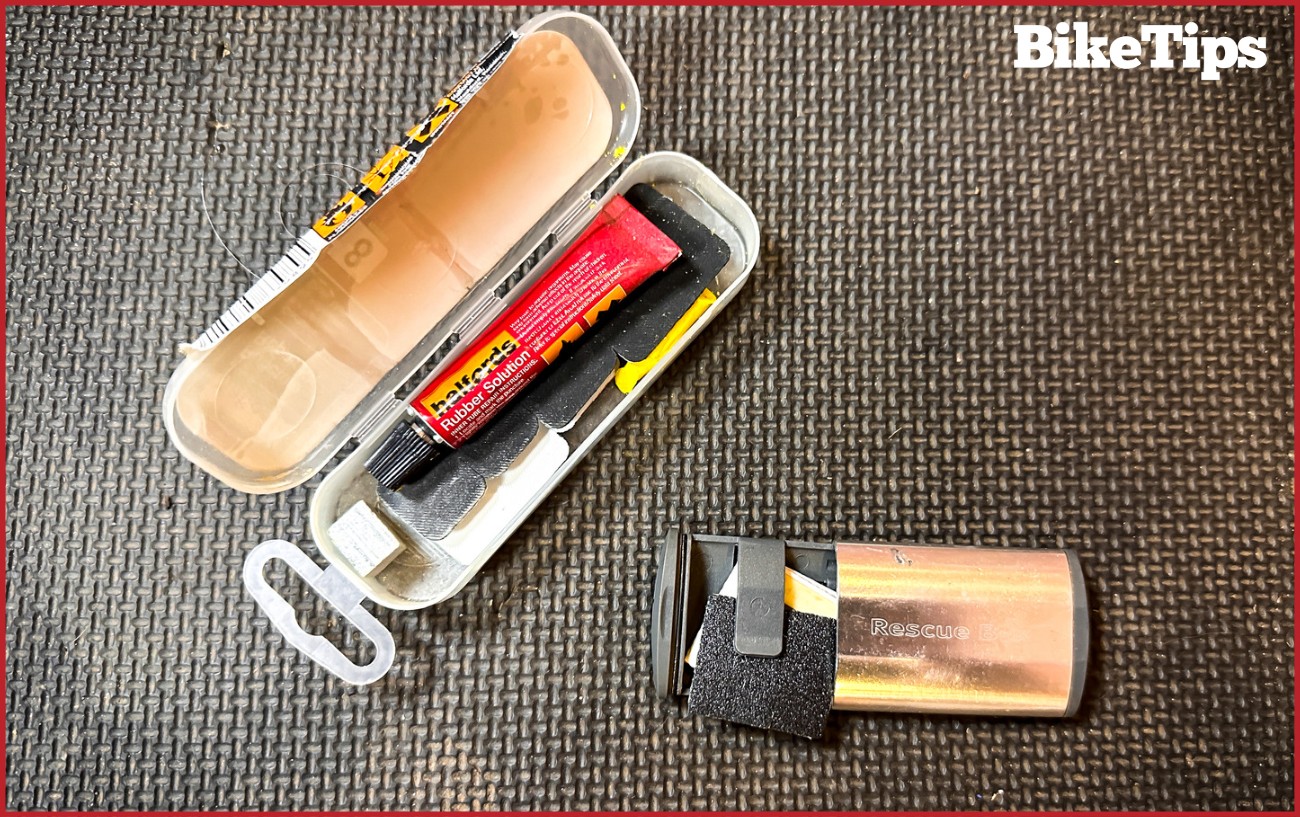 Two tire patch kits sit on a black floor mat with their contents exposed.