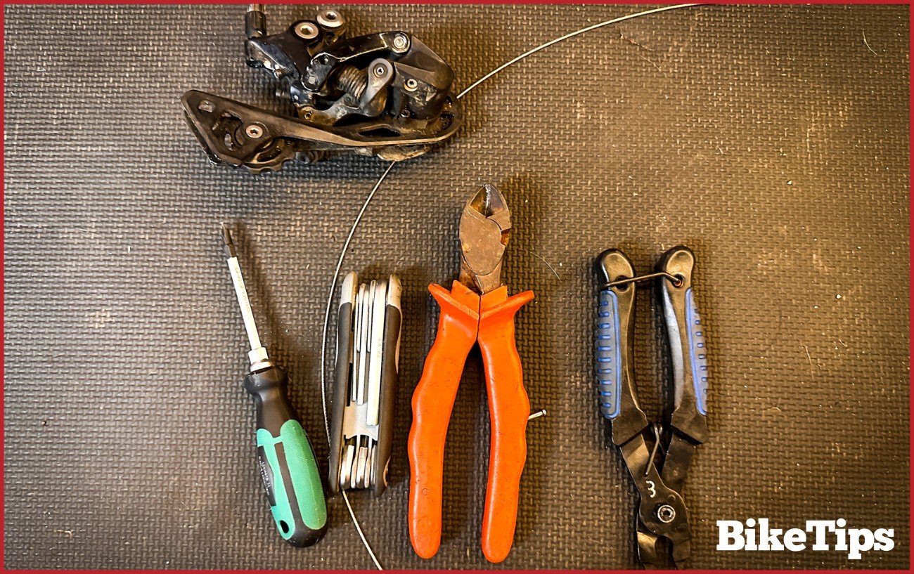The tools for installing a bikes rear derailleur, including allen keys, screwdriver, cable cutters, and bolt cutters.