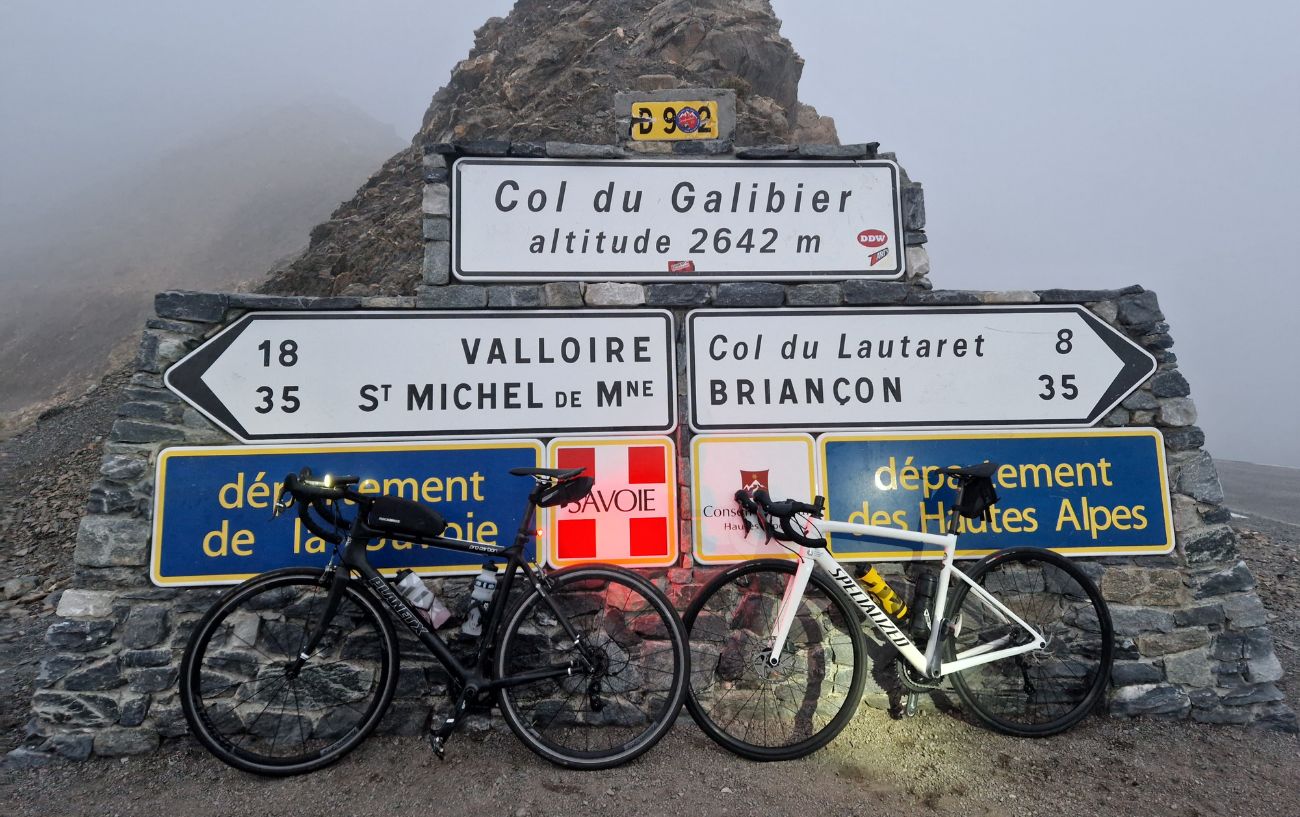 Road signs at the summit of the Col du Galibier, with bikes leaning against them.