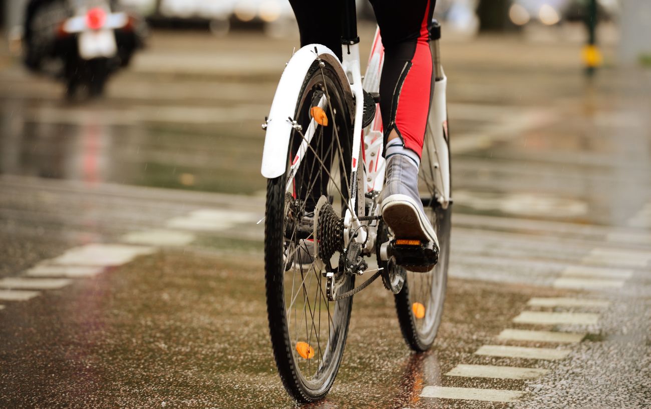 Close-up on the back wheel of somebody cycling in the rain.