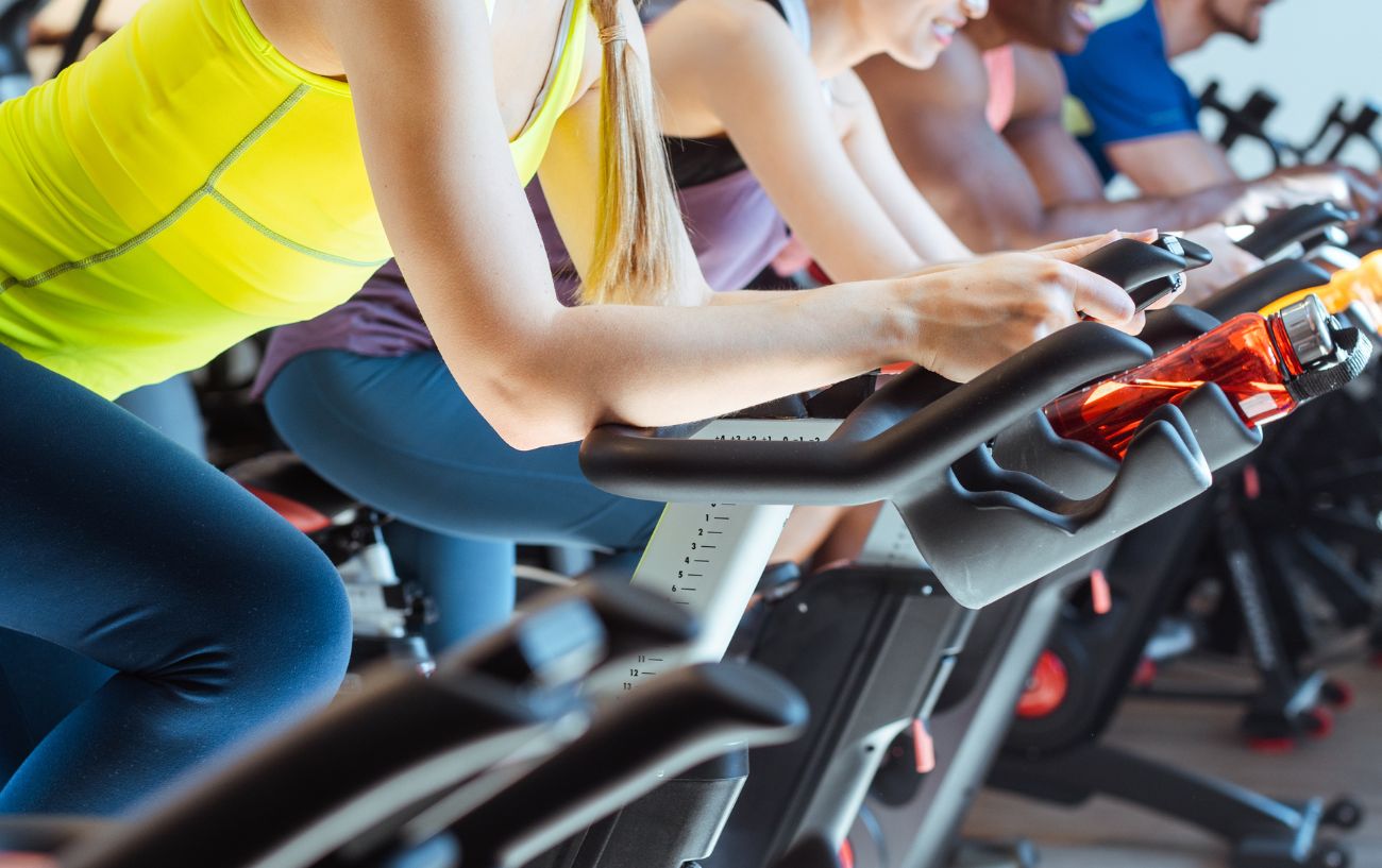 A group of indoor cyclists with their hands on the armrests.