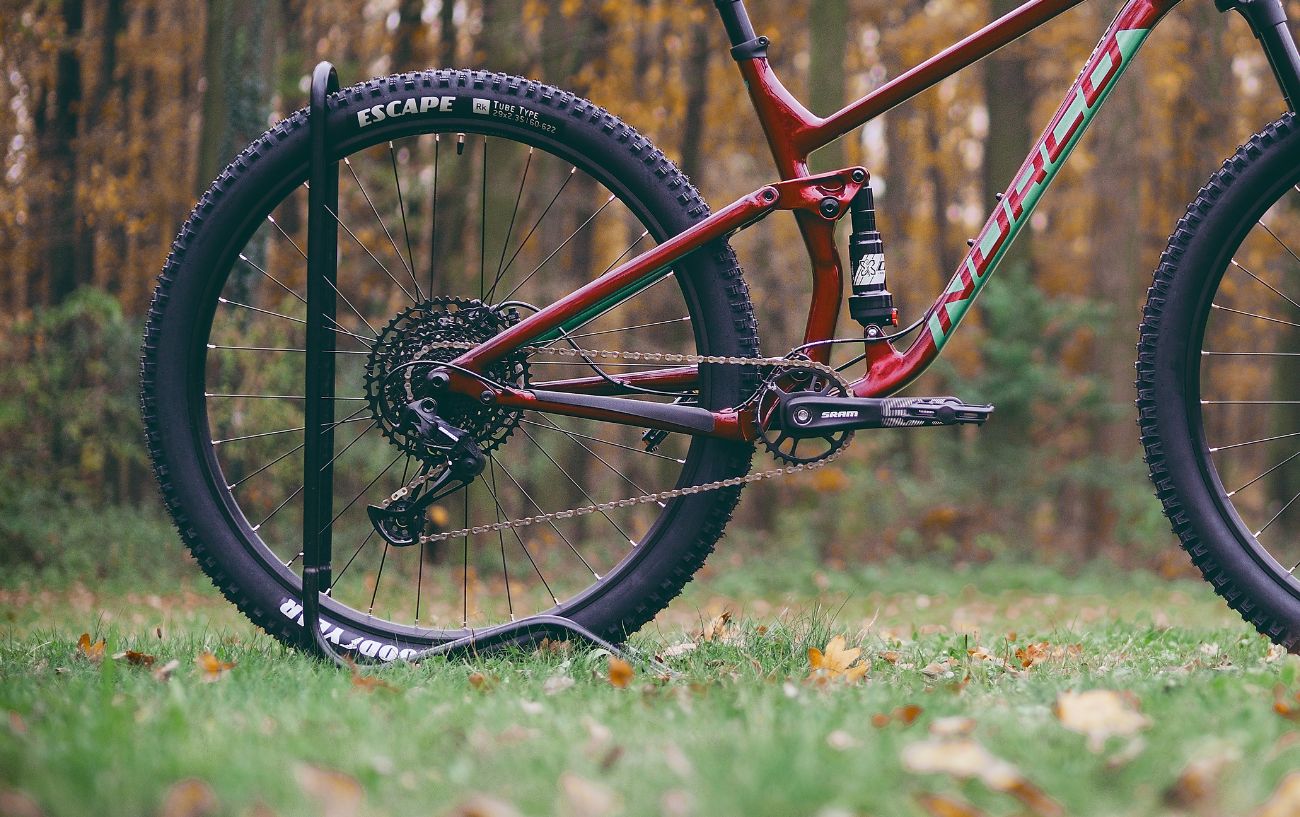 A burgundy mountain bike sits in a forest clearing.