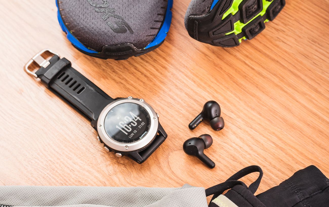A Garmin watch lies on a wooden floor.