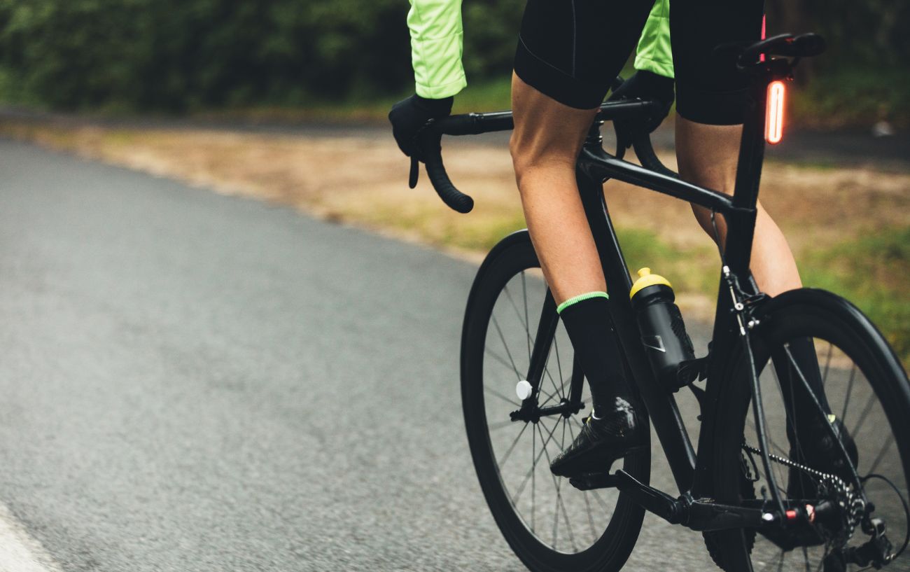 A cyclist rides a black road bike in the rain.