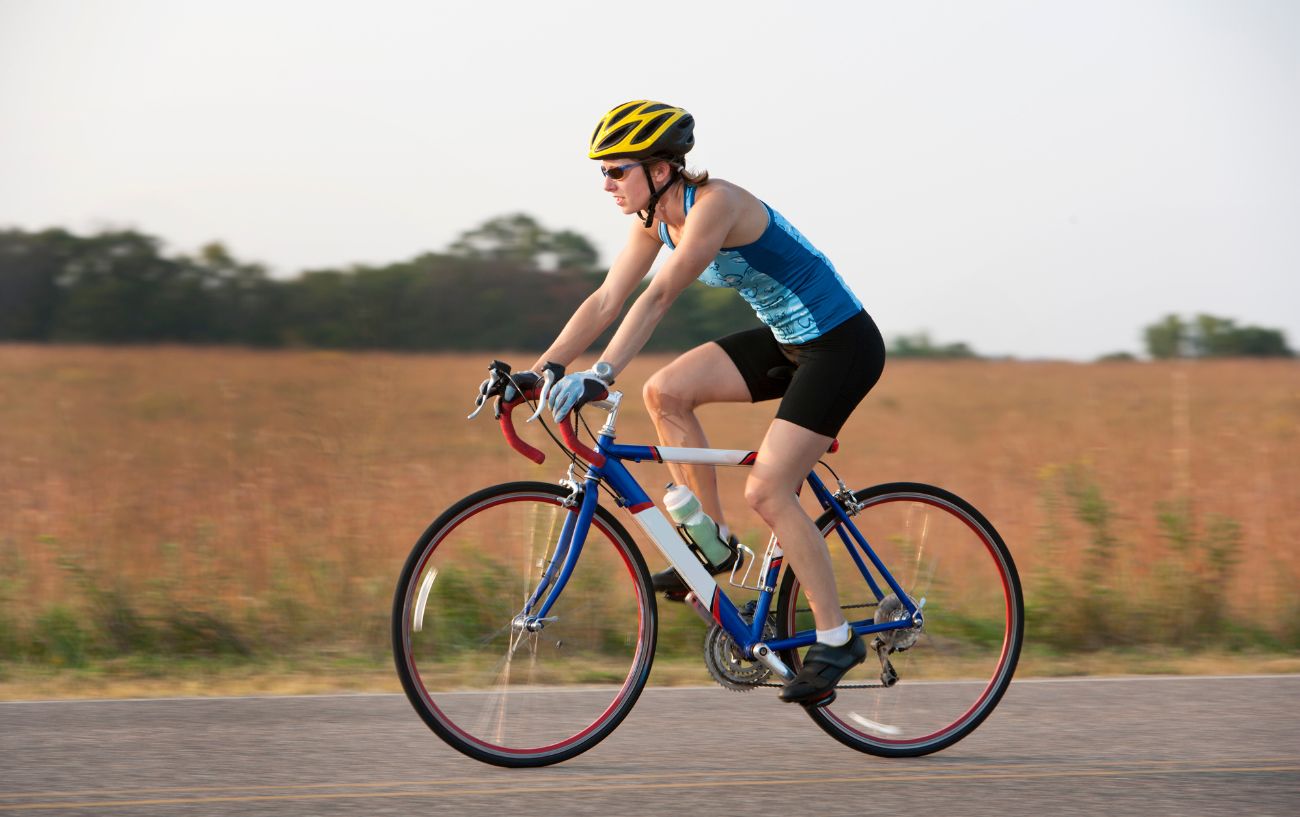 A woman rides a blue and white road bike.