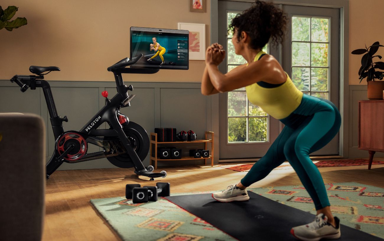 A woman does a stretching workout on the screen of her Peloton bike.