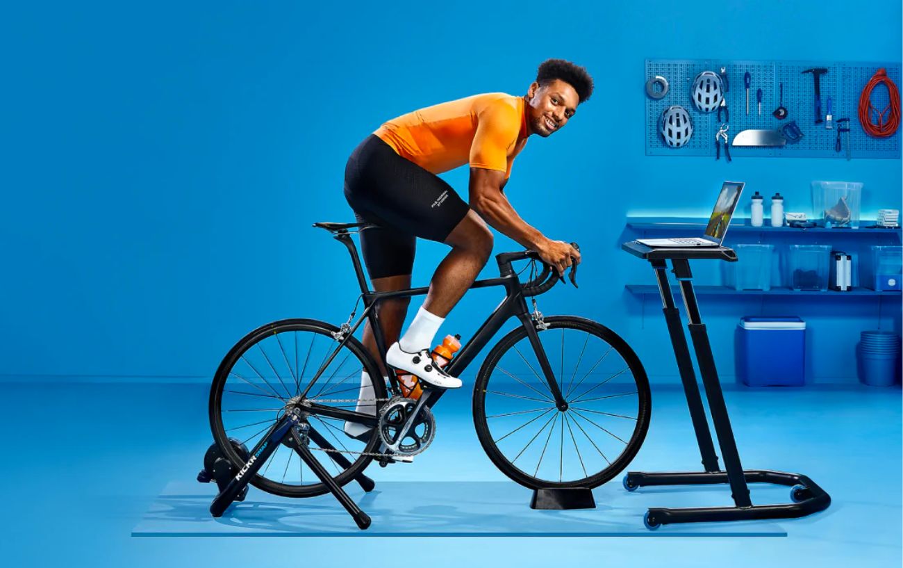 A cyclist rides his Zwift in a blue-painted room in a Zwift promotional image.