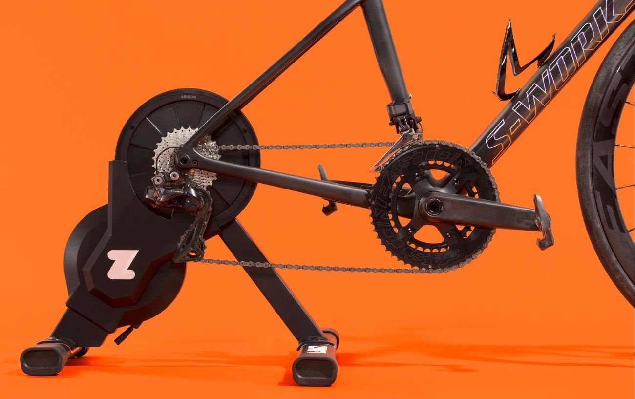 Close-up of the Zwift Hub smart trainer against an orange background.