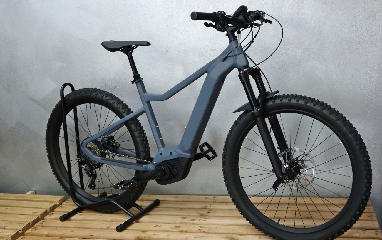 A grey electric mountain bike on a wooden bench.
