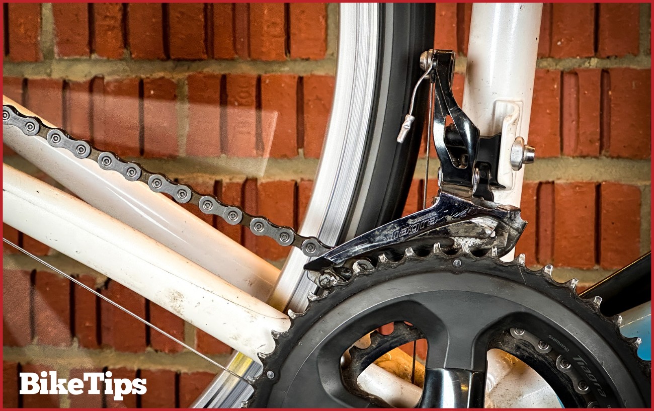 A spinning rear wheel of a bike with a Shimano Claris front derailleur and crankset.