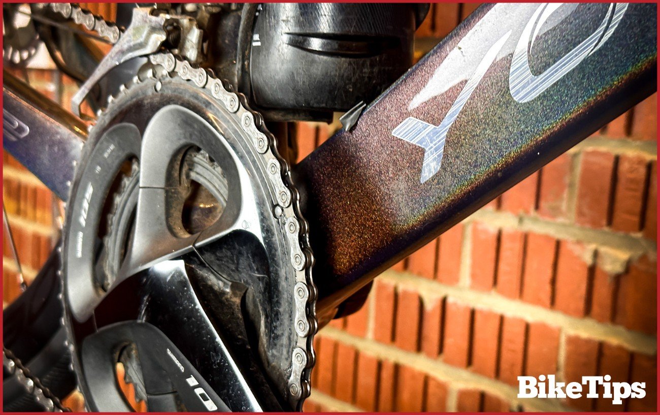 The chainrings of a road bike while sitting in a stand against a brick back wall.