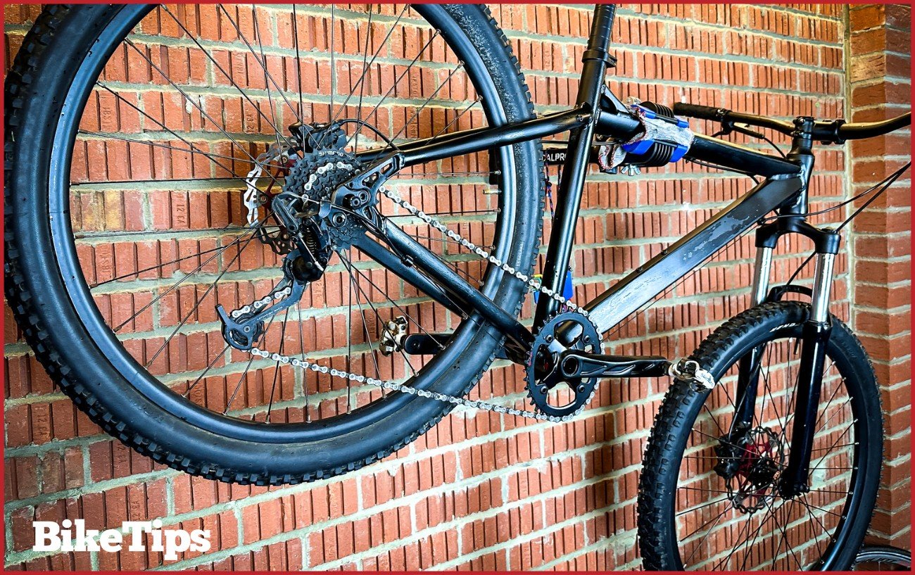 A matte black mountain bike in a wall bike stand.