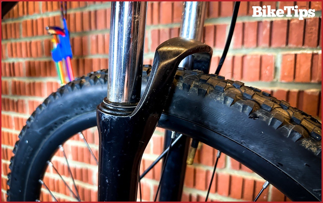 A mountain bike fork against a brick background.