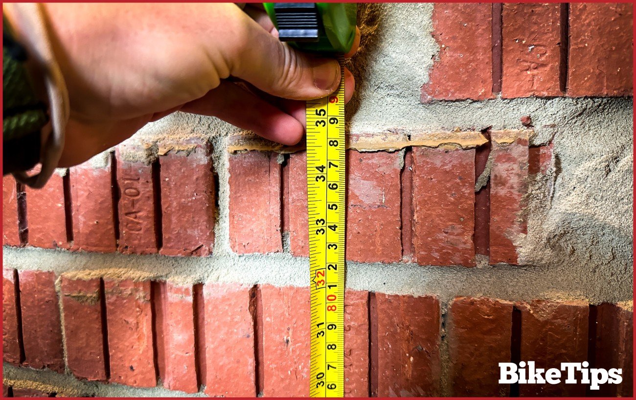 Measuring a mark on a wall where a cyclist has measured his inseam.