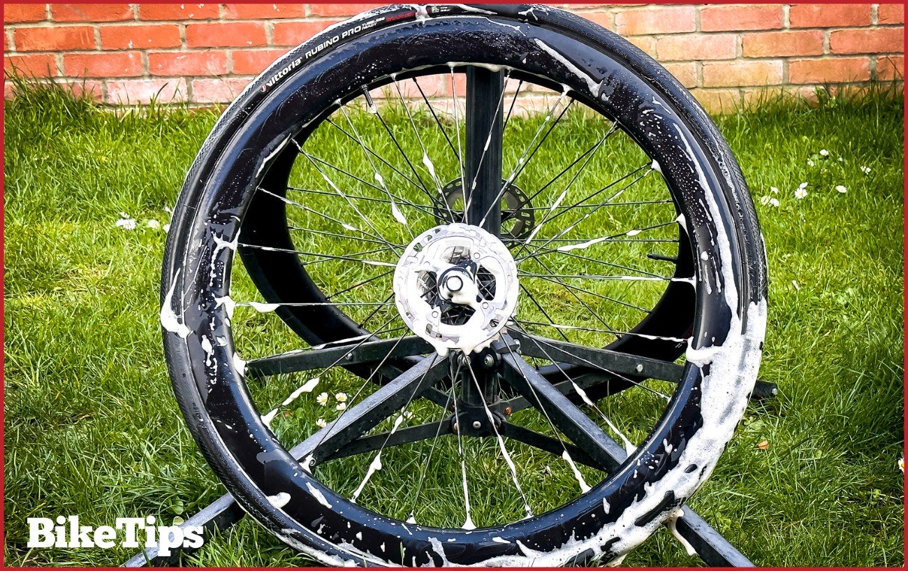 A wheel which has been removed from a bike and is covered in bike wash.