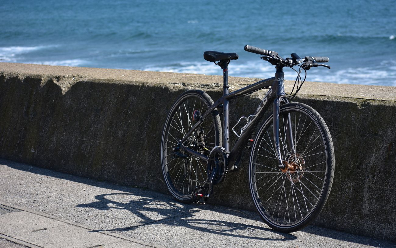 A hybrid bike leans against a coastal wall.