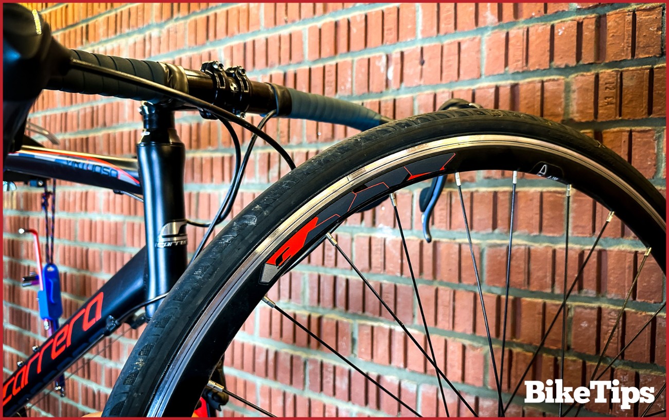 A 700c wheel up against a set of road bike handlebars.