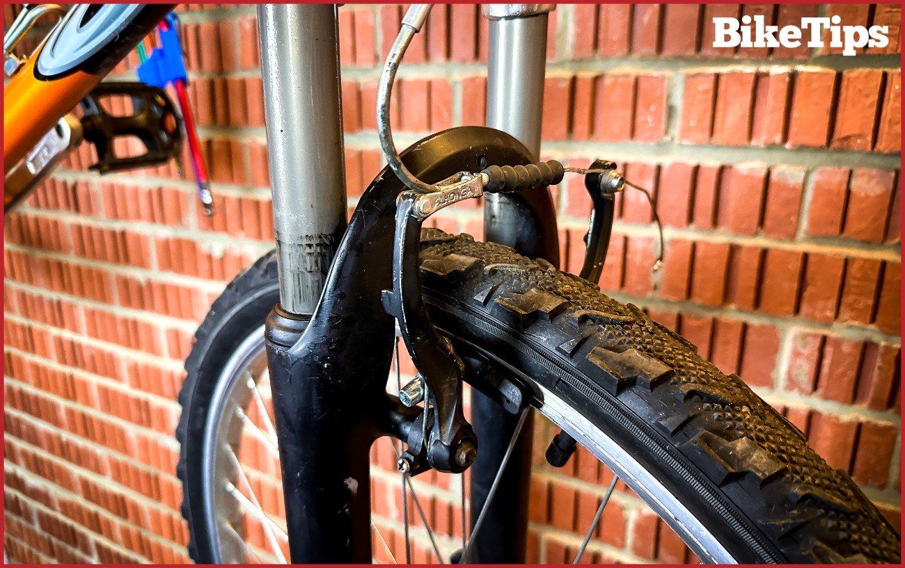 A V Brake on a mountain bike against a brick background.