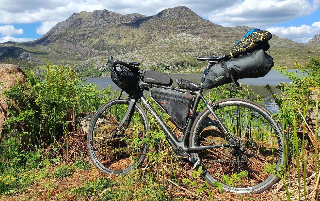 View of a fully-loaded touring bike with a Scottish mountain in the background.