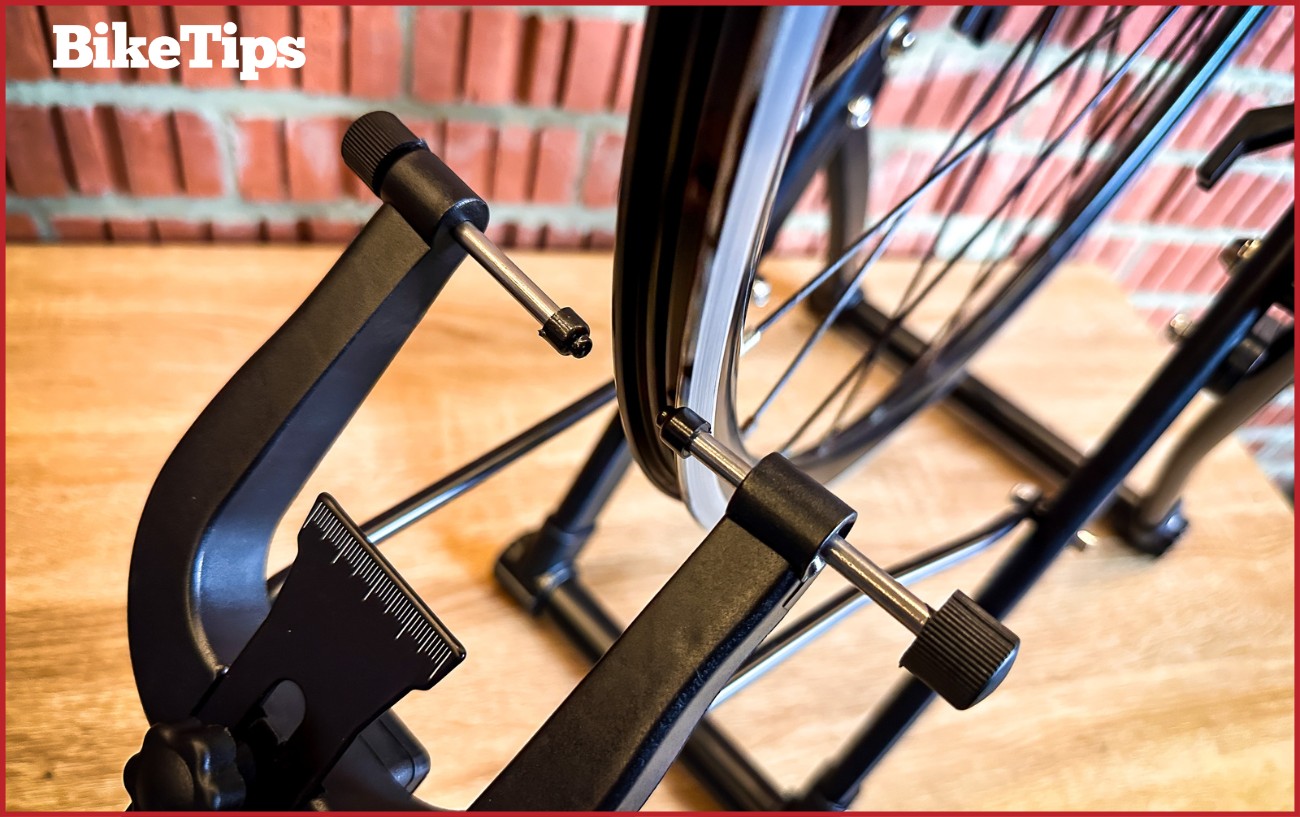 The marking pins of a truing stand with a bike wheel inside.