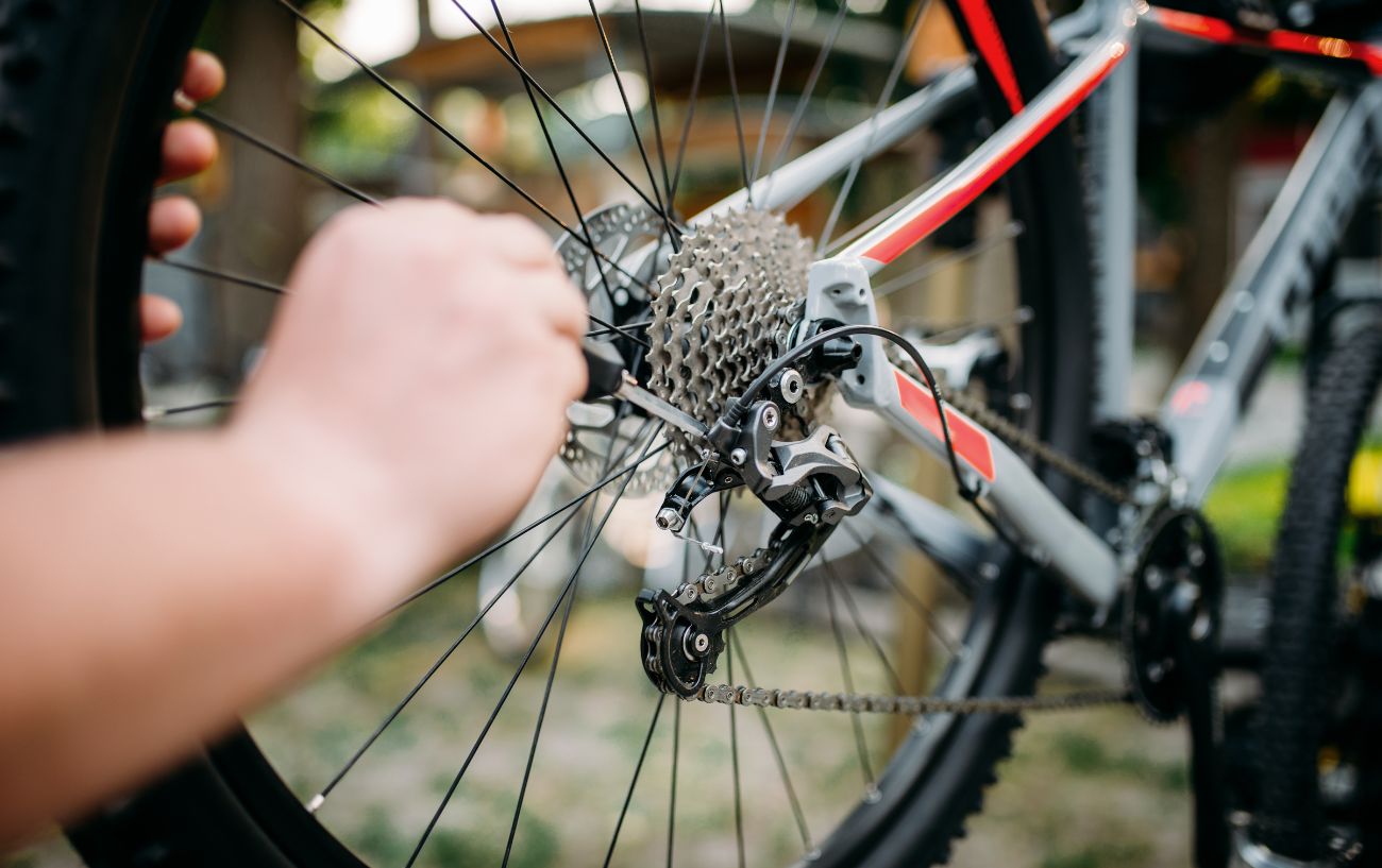 A cyclist makes some adjustments to their rear derailleur.