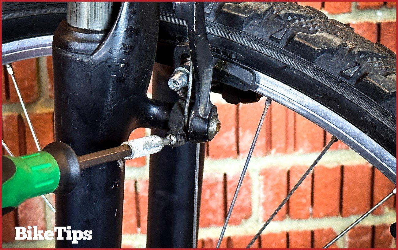 Using a Phillips Screwdriver to adjust the arm of a V brake on a mountain bike suspension fork. 