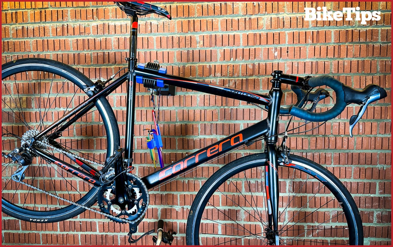 A road bike in a wall stand with hanging hex keys.