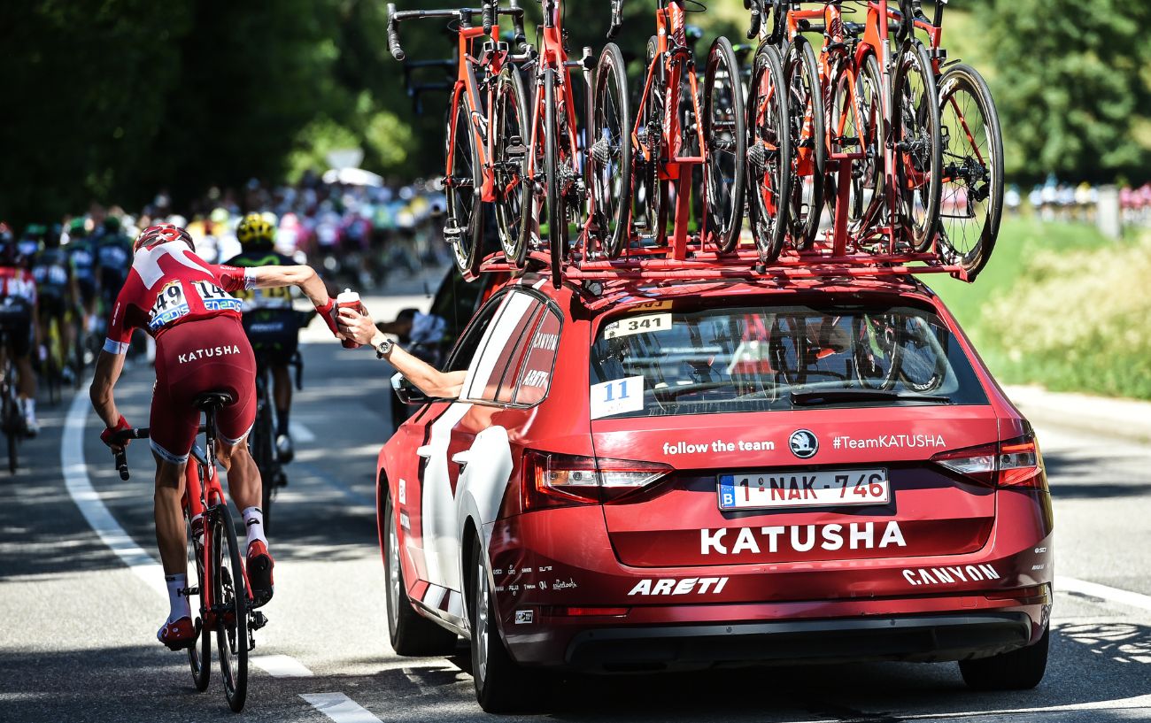 A domestique collects a water bottle at the Tour de France.