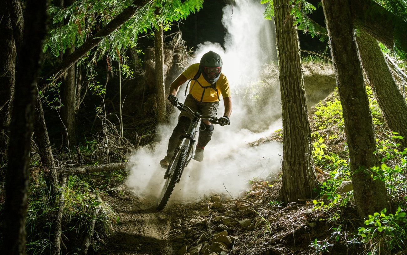 A cyclist descends through a forest at night while downhill mountain biking.