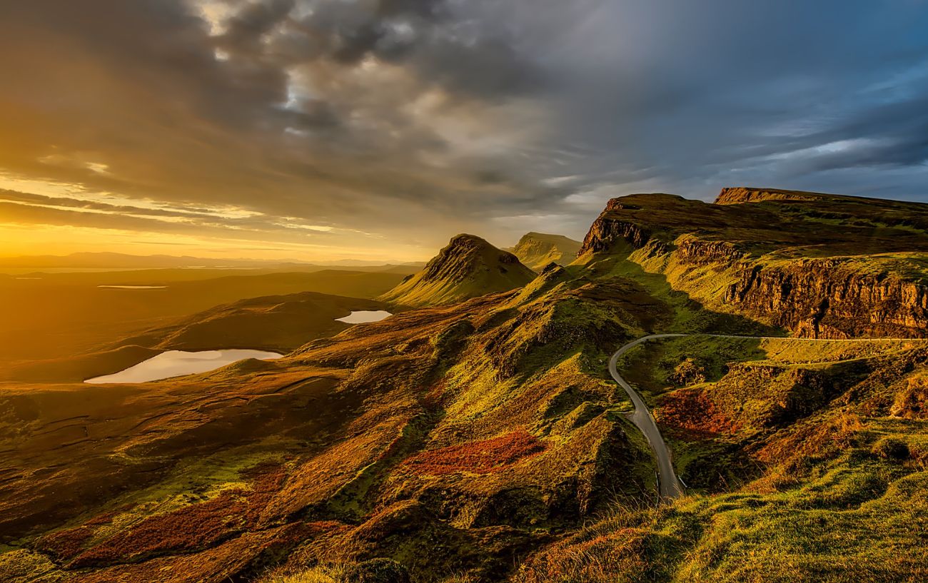 A road snakes down the Scottish cliffs at sunset.