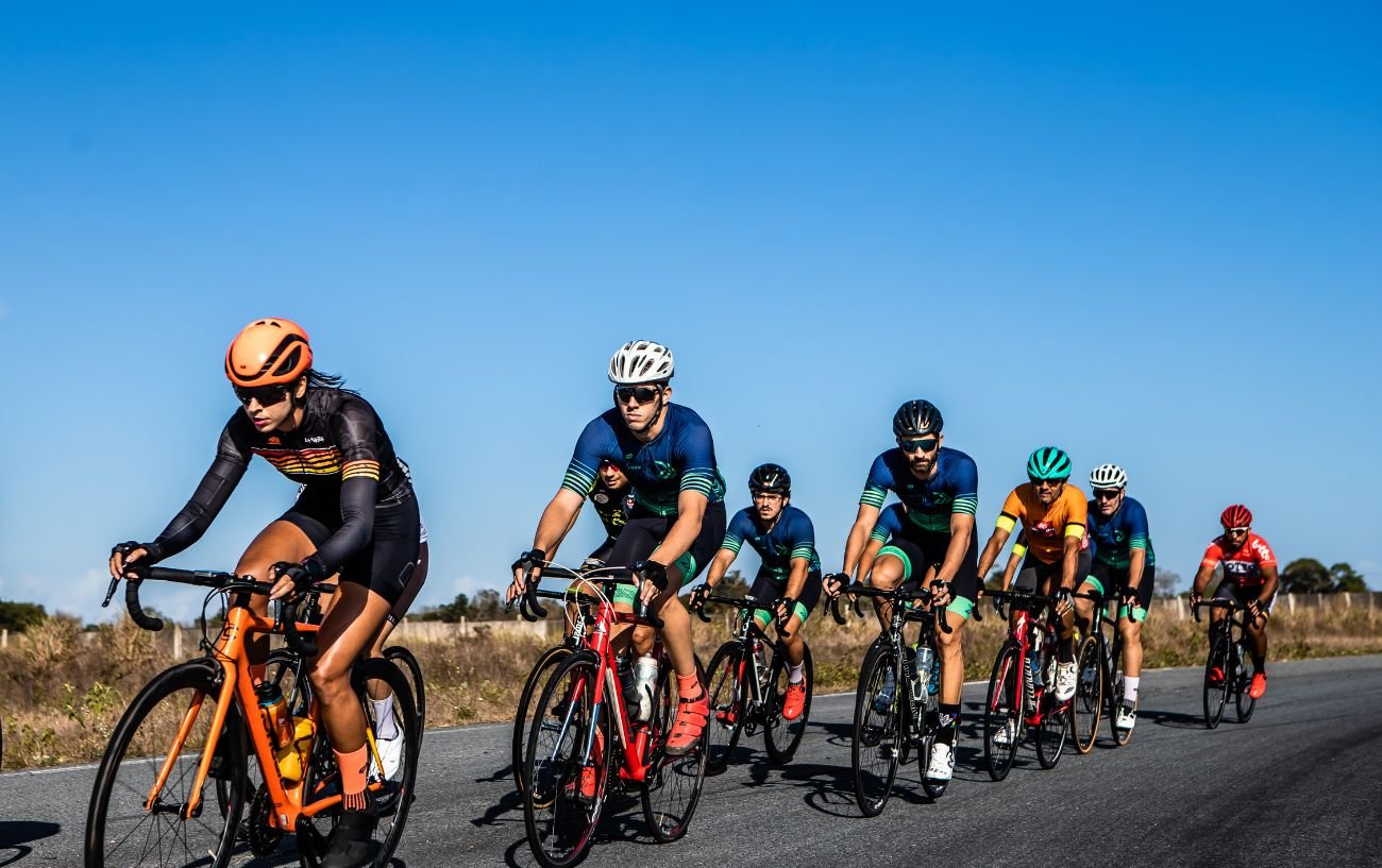 A group of road cyclists cycle in a group on a clear day. 