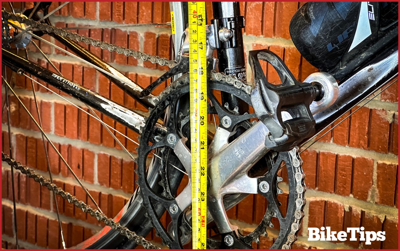 A crank with a tape measure across it measuring the seat tube. 