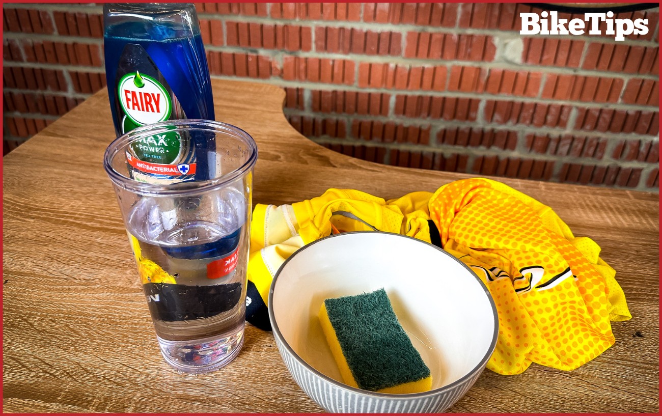 Dishwashing liquid, a bowl, sponge, water, and a dirty bike jersey.