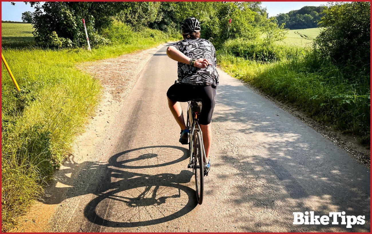 A cyclist showing a going around signal while riding a road bike.