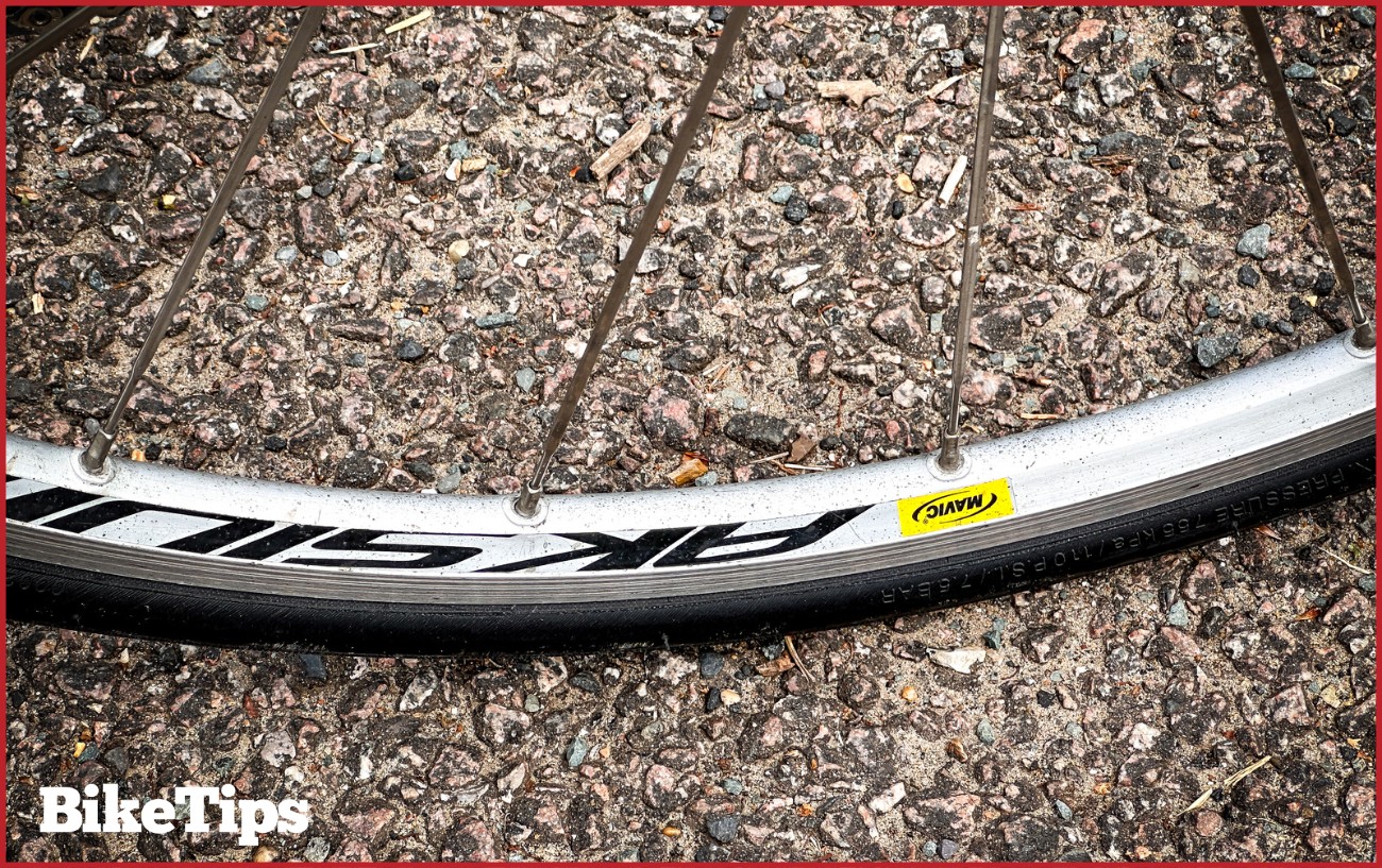 A road bike wheel on rough pavement.