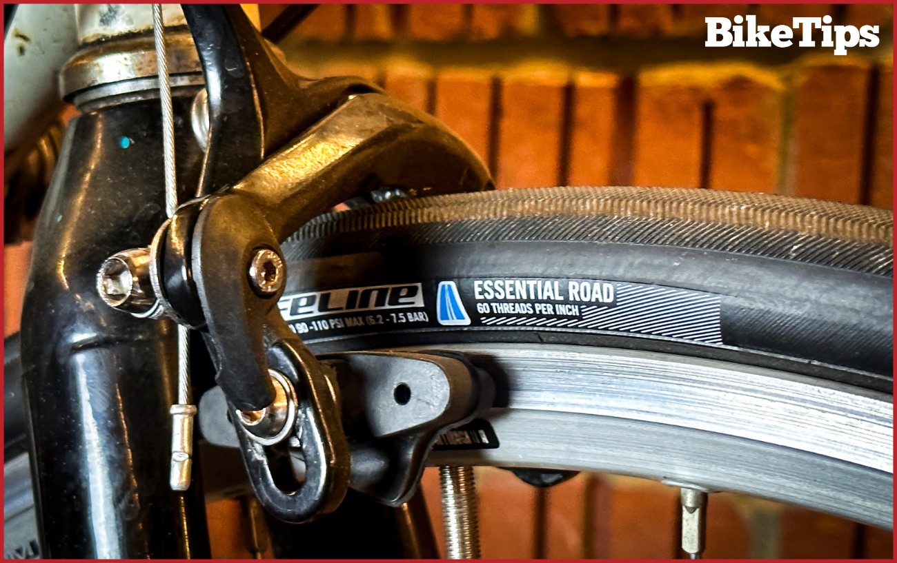 A road bike front brake against a red brick wall.