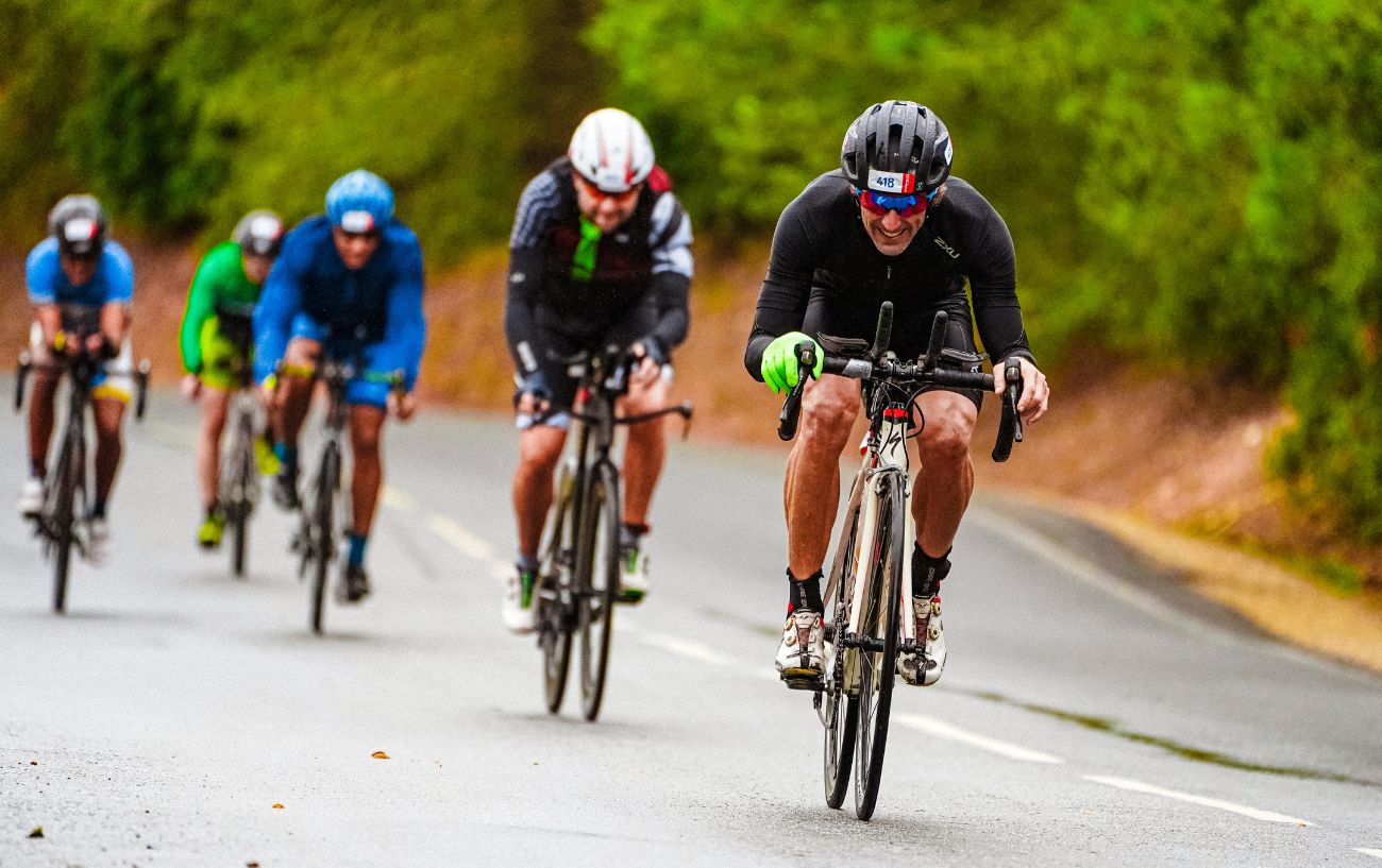 Bicycle race with five riders cycling downhill on tarmac road. 