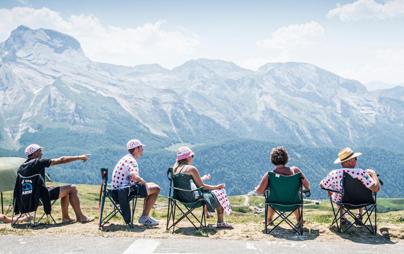 A group of cycling fans sit by the roadside in the French Alps, waiting for the Tour de France to approach.